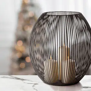 Stor oval lanterne med åbent metaltrådsdesign og tre tændte stearinlys indeni.