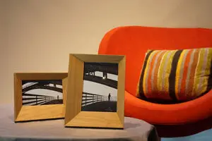To trærammer med brofoto på bord, moderne design. Orange stol i baggrunden.