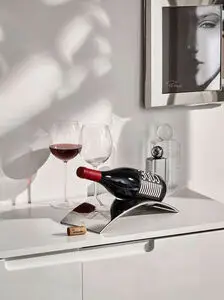 Vinkaraffelholder med buet design, vinflaske vandret, to vinglas, enkelt og stilrent interiør.
