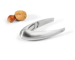 Elegant nøddeknækker i metal med kurvet design ved siden af en valnød og en hasselnød for skala.