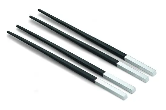 To par sorte spisepinde med tilspidsede ender og firkantede metalhåndtag, arrangeret parallelt.