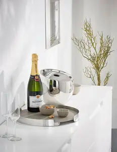 Poleret Philippi Froid isspand med oval form, champagneflaske og glas på hvid overflade.