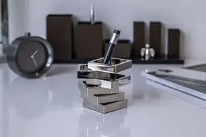 Penneholder med vinklet design og reflekterende overflade. Holder en pen lodret på et skrivebord.