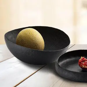 Ovalformet skål med tekstur, indeholder melon, står på træbord.