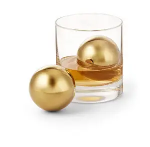 To guldfarvede kugler, én i et glas med væske, én ved siden af.