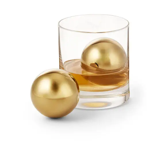 To guldfarvede kugler, én i et glas med væske, én ved siden af.