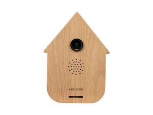 Lyst træhusformet ur med spidst tag, cirkulær linse, højtalerhuller og "Karlsson" på forsiden.