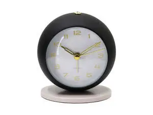 Rundt vækkeur med sort ydre, varm grå base, guld-tal og visere på hvid skive, knap øverst.
