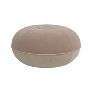 Rund pouf i varm sand og lys tone, med knap i midten og segmenter strålende ud fra centrum.