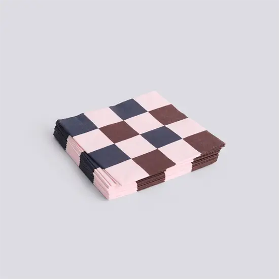 Servietter med ternet mønster i lys pink, mørkebrun og marineblå, stablet på en lys baggrund.