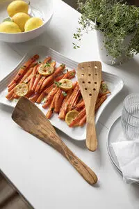 To træredskaber af oliventræ ved en tallerken med gulerødder og citroner.