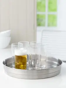 Rund, skinnende metalbakke med flere glas, hvoraf ét er fyldt med øl med skum.