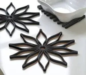 Sort silikone bordskåner med blomstermotiv, stort og småt sæt, set ved siden af et fad.