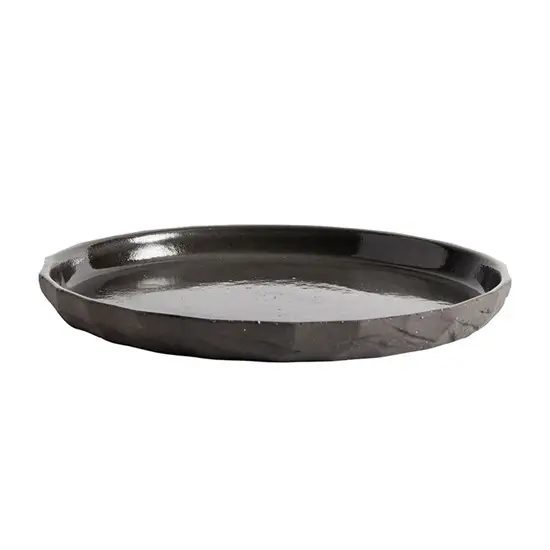 Rund tallerken i mørk farve med ujævne kanter, diameter ukendt.