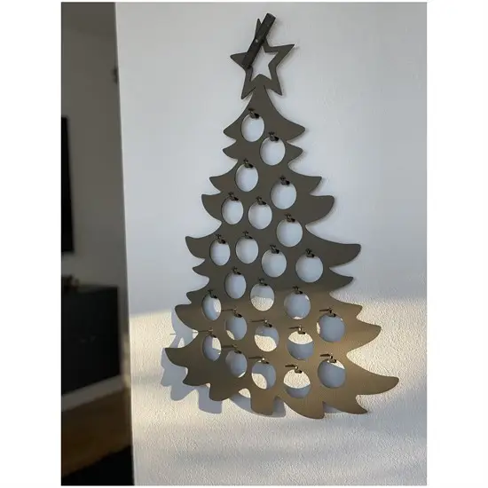 Grå julekalender i form af juletræ med stjerne og runde udskæringer, hængende på væg.